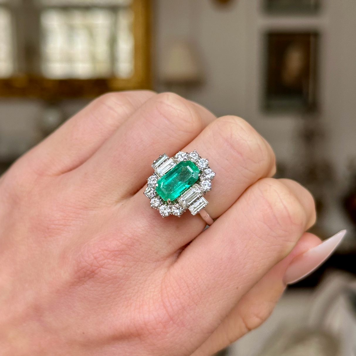 Vintage emerald and diamond cluster ring, worn on closed hand.