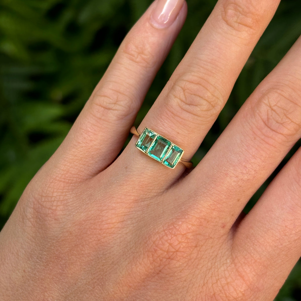 Vintage, 1930s three-stone emerald ring worn on hand.