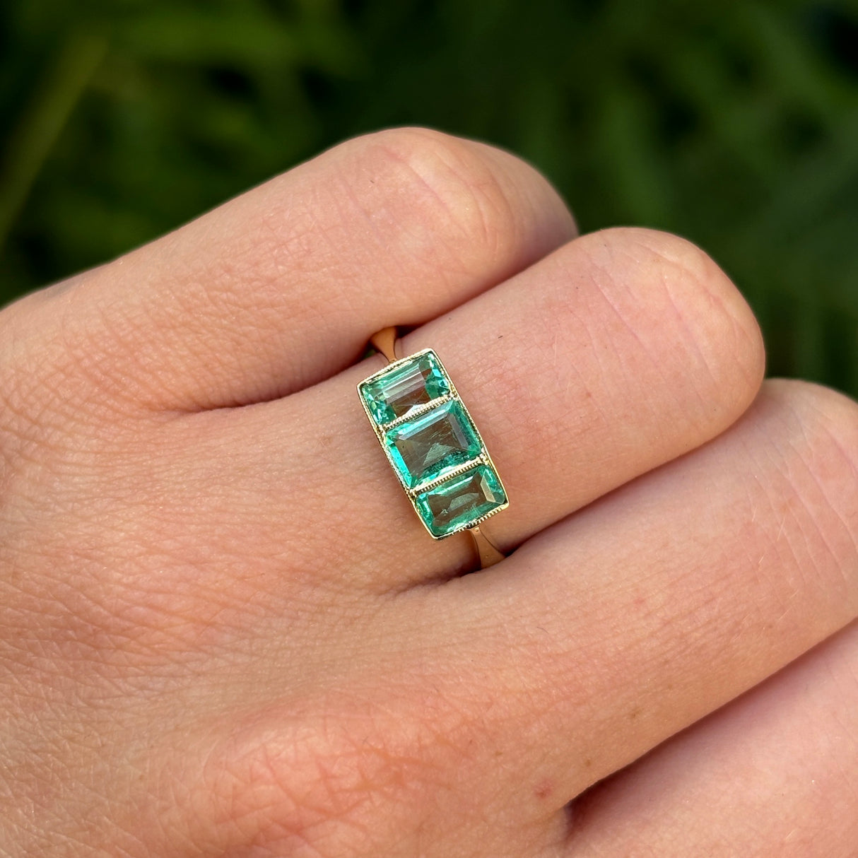 Vintage, 1930s three-stone emerald ring worn on hand.