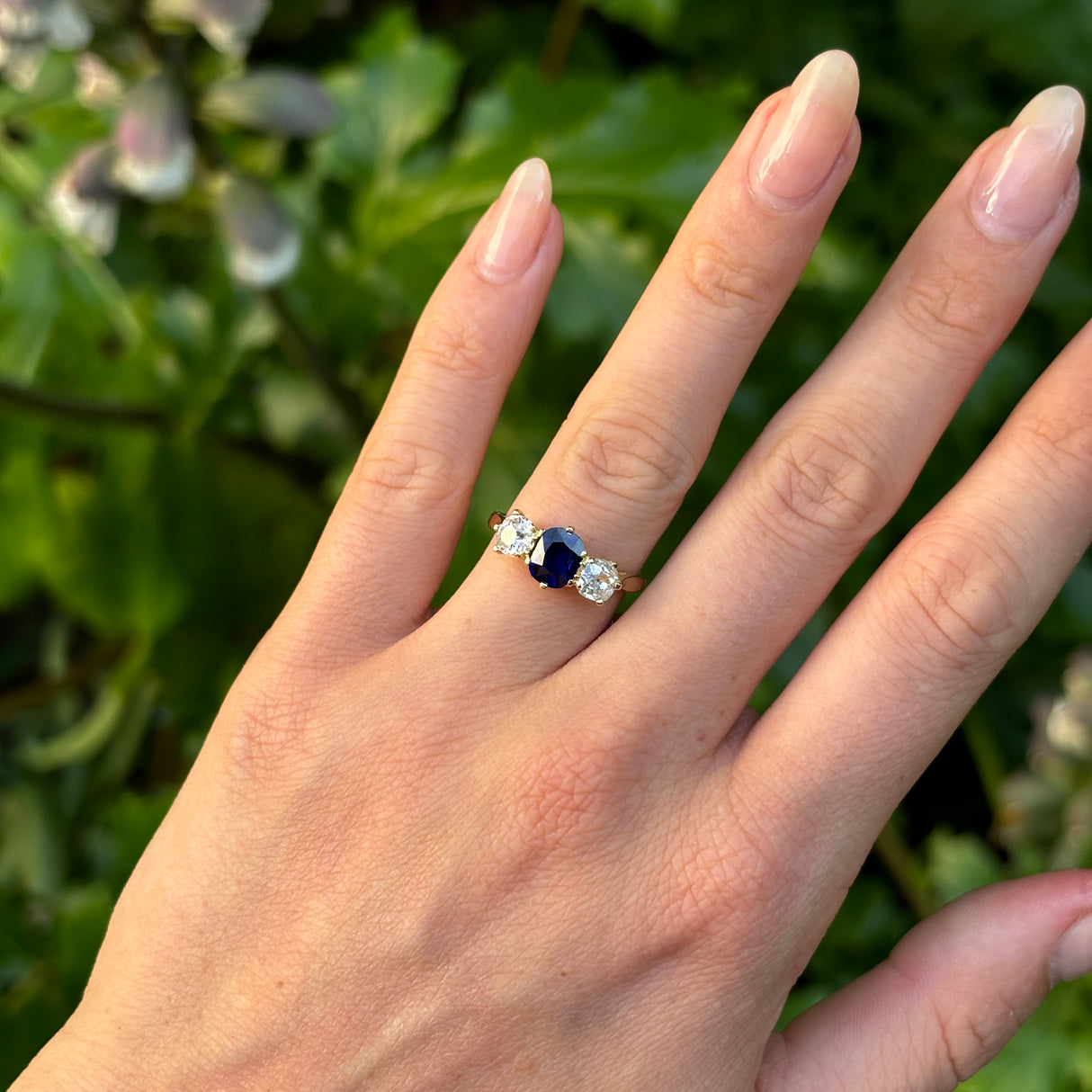 Vintage, 1980s sapphire and diamond three-stone ring worn on hand.