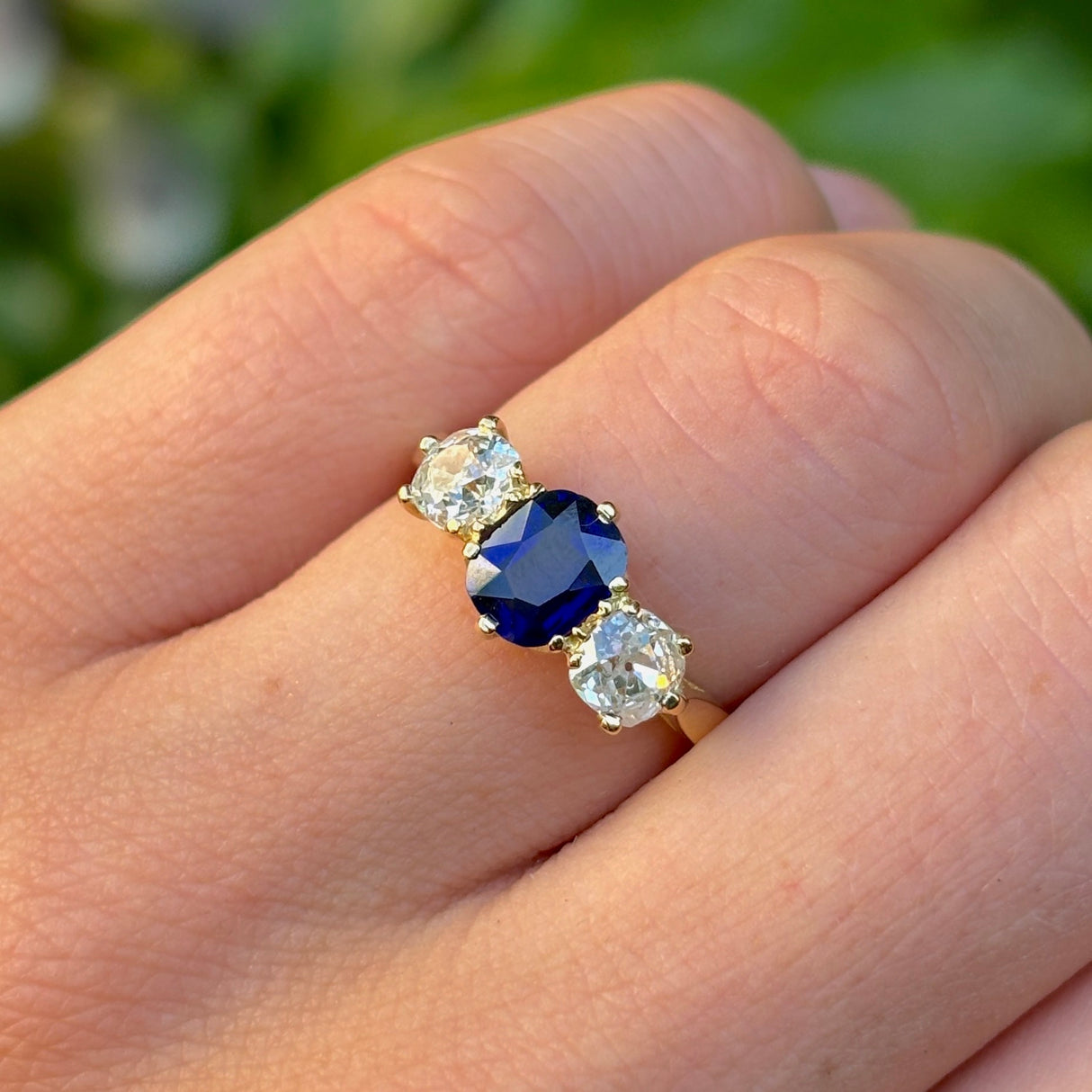 Vintage, 1980s sapphire and diamond three-stone ring worn on hand.