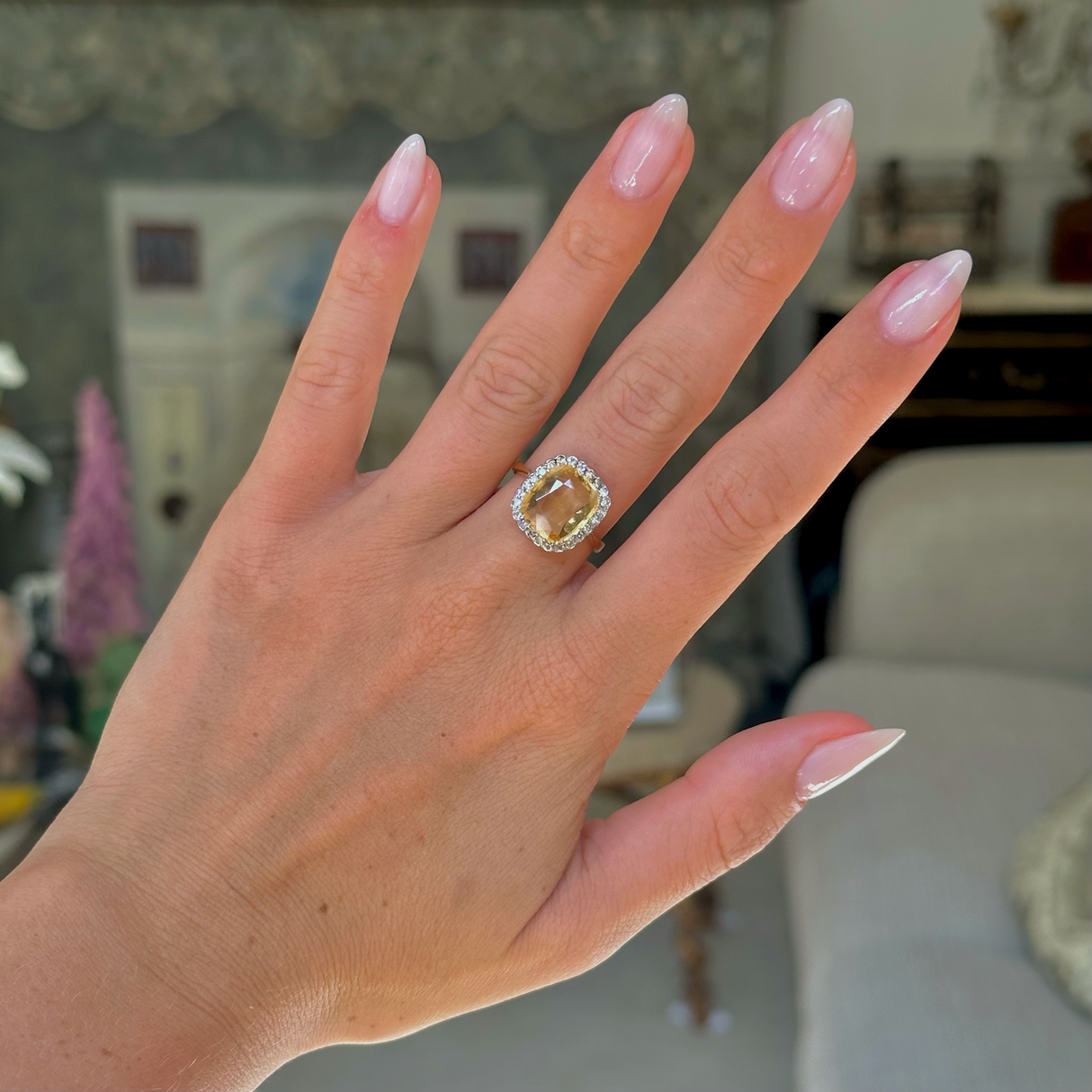 Yellow sapphire and diamond cluster ring, worn on hand, front view.