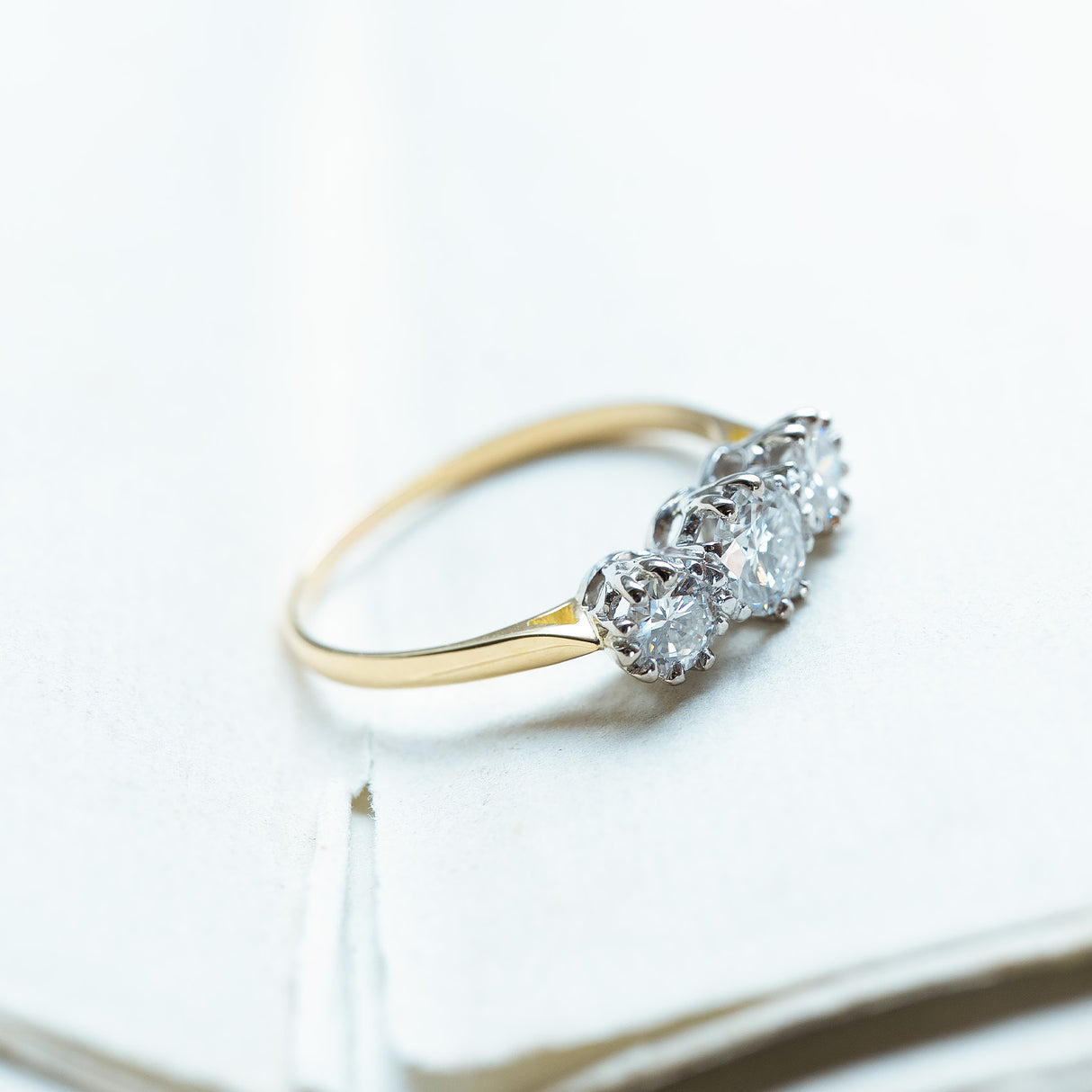 Antique Art Deco diamond three-stone ring with graduated diamonds and yellow gold band.