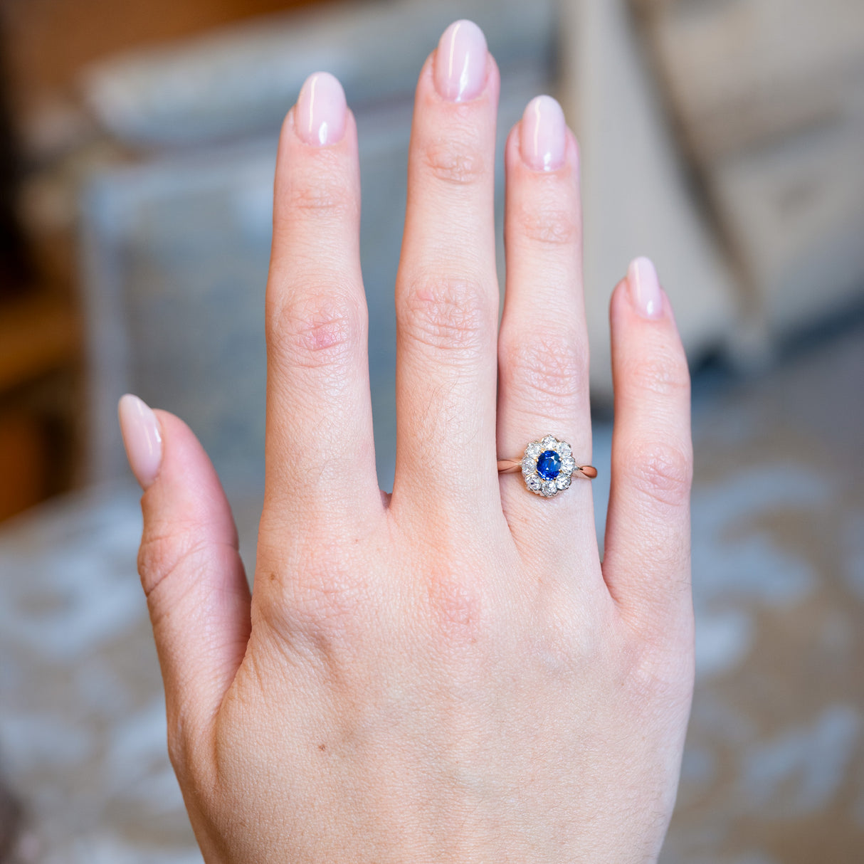 Antique Belle Époque sapphire and diamond cluster engagement ring worn on hand.