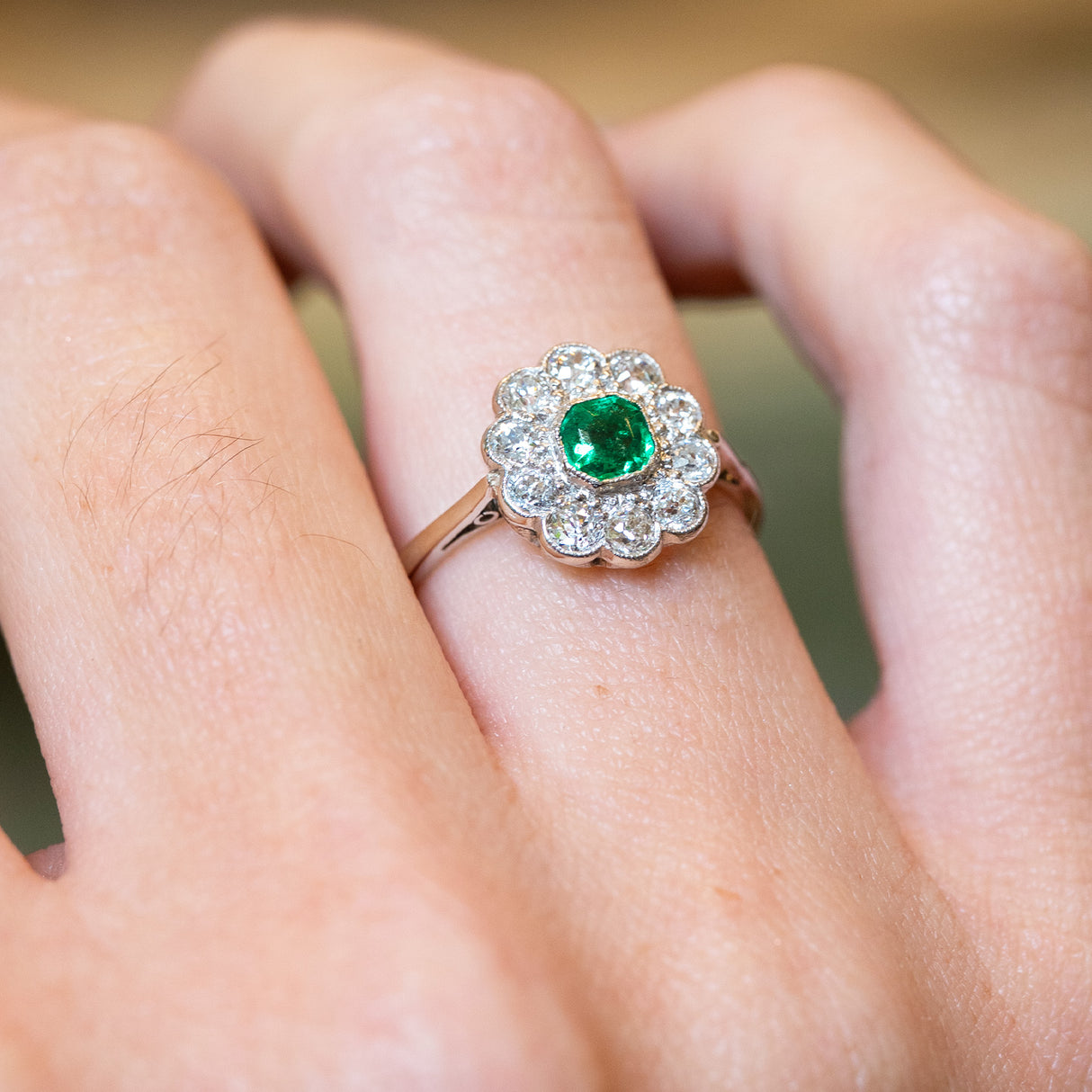 Antique Edwardian emerald and old-mine cut diamond cluster ring with raised cluster setting.