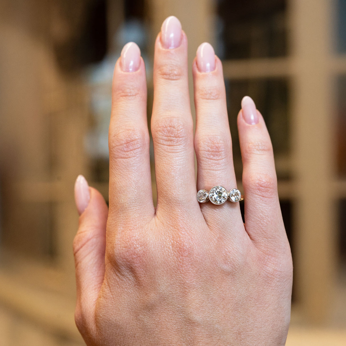Hand wearing an antique Edwardian old-cut diamond ring with a blurred background