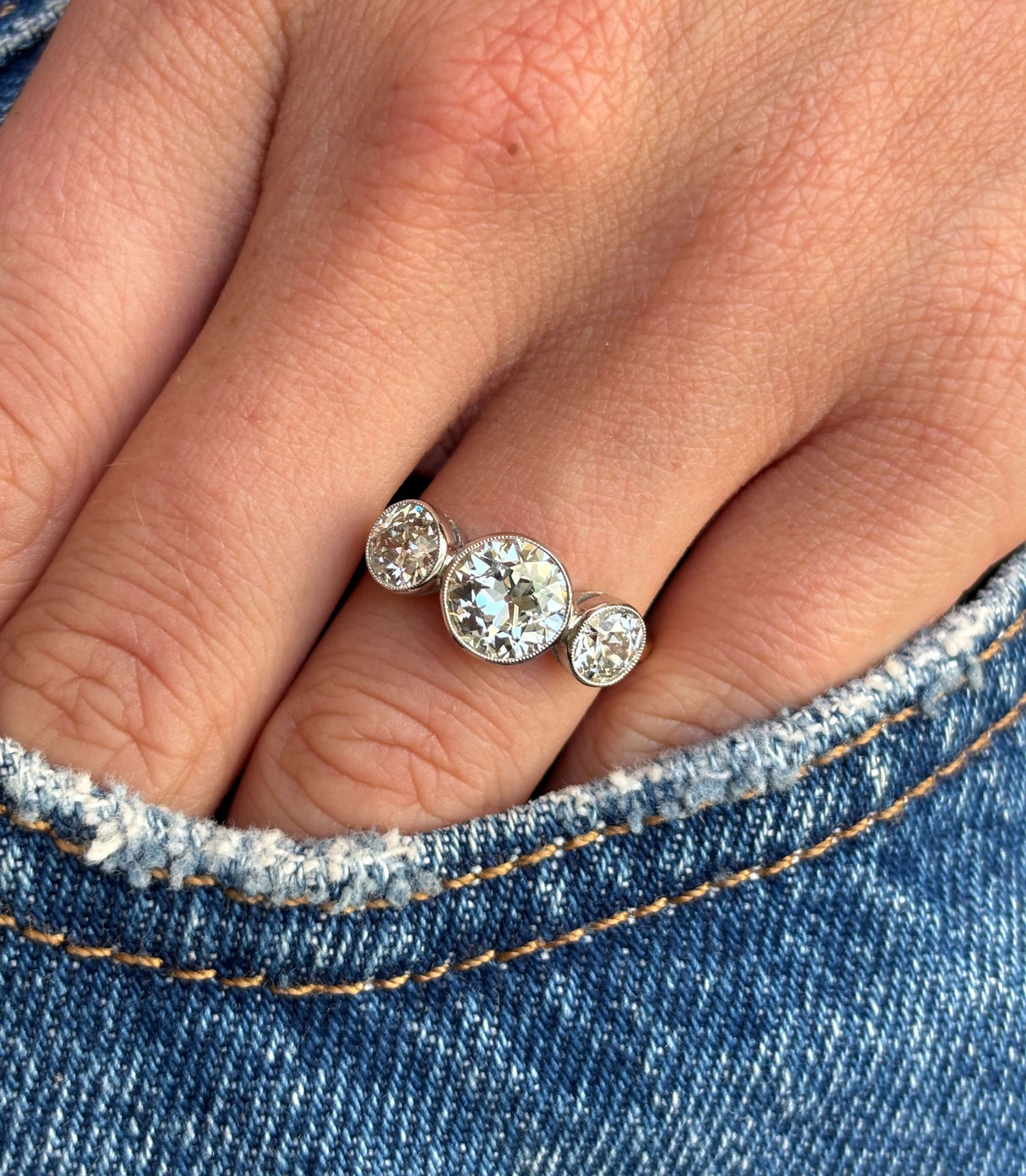 Antique Edwardian old-cut diamond three-stone engagement ring set with three old-cut diamonds, worn on a hand.