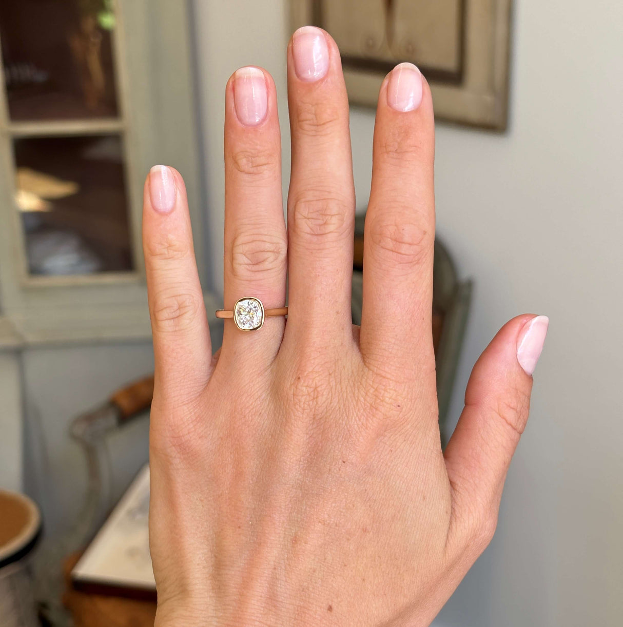 Antique-inspired cushion old-cut diamond solitaire engagement ring worn on hand showcasing its classic heirloom-inspired design