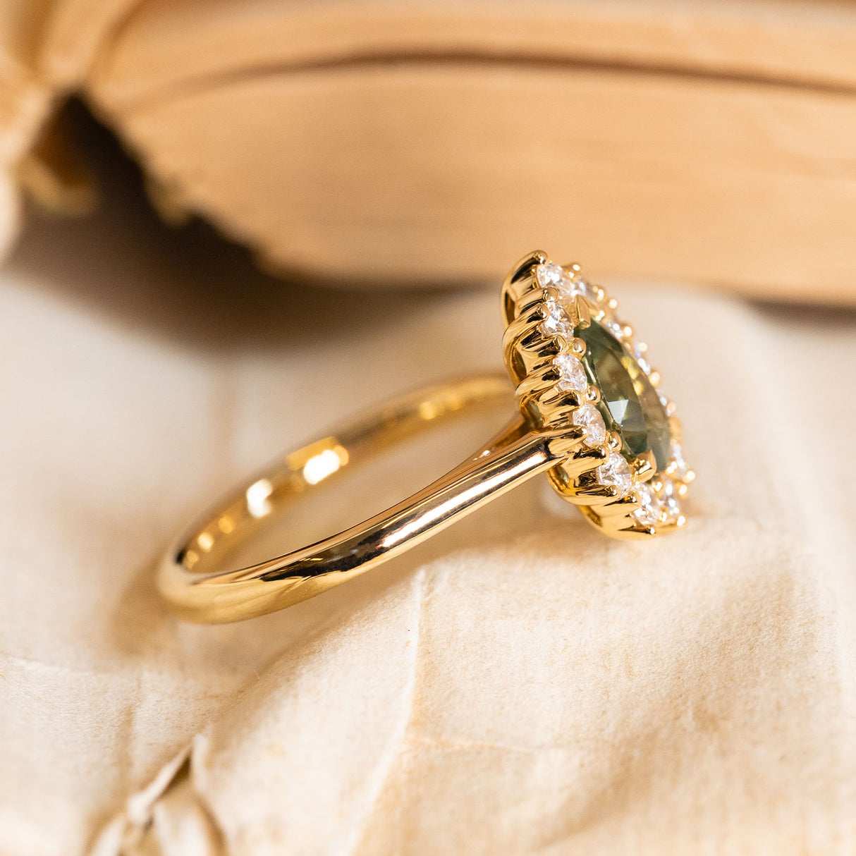 Vintage-style pear-cut green sapphire and diamond cluster ring showcasing a green sapphire centre stone encircled by diamonds in yellow gold.