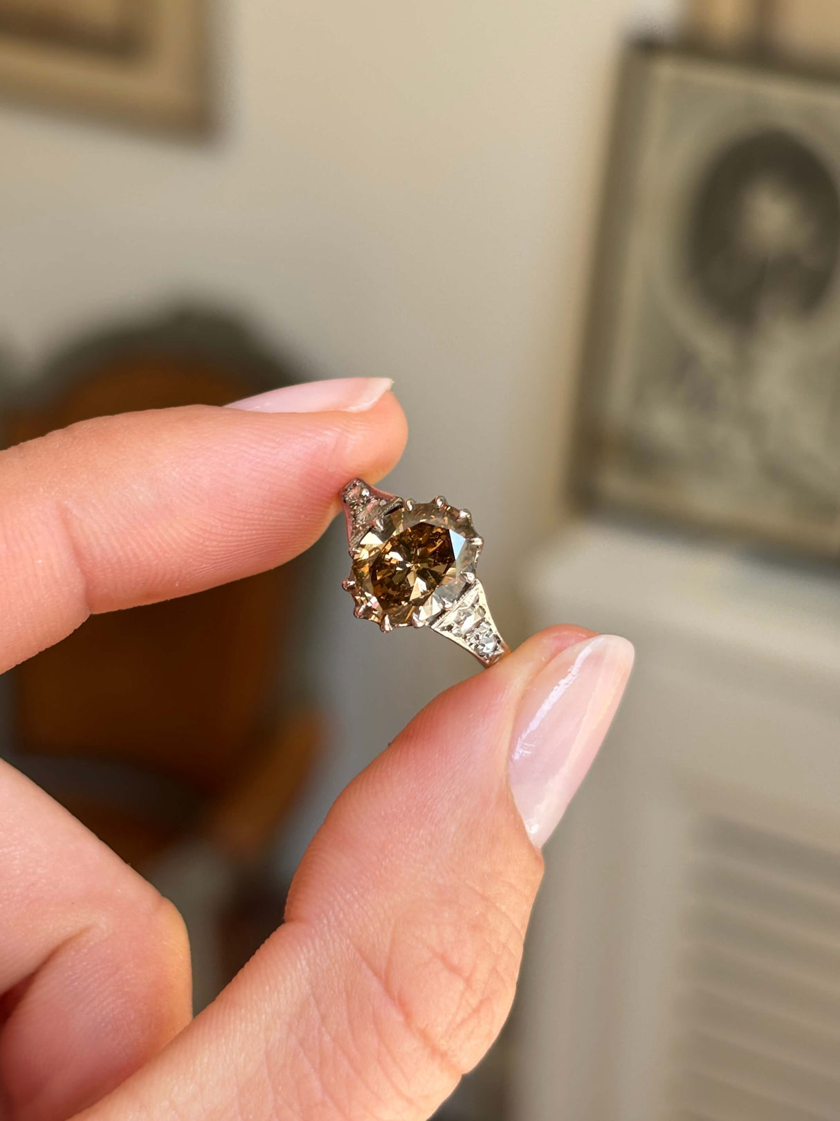 Antique-inspired hazelnut-brown diamond and rose-cut diamond engagement ring featuring a hazelnut-brown diamond centre stone with rose-cut diamond accents, held by hand.