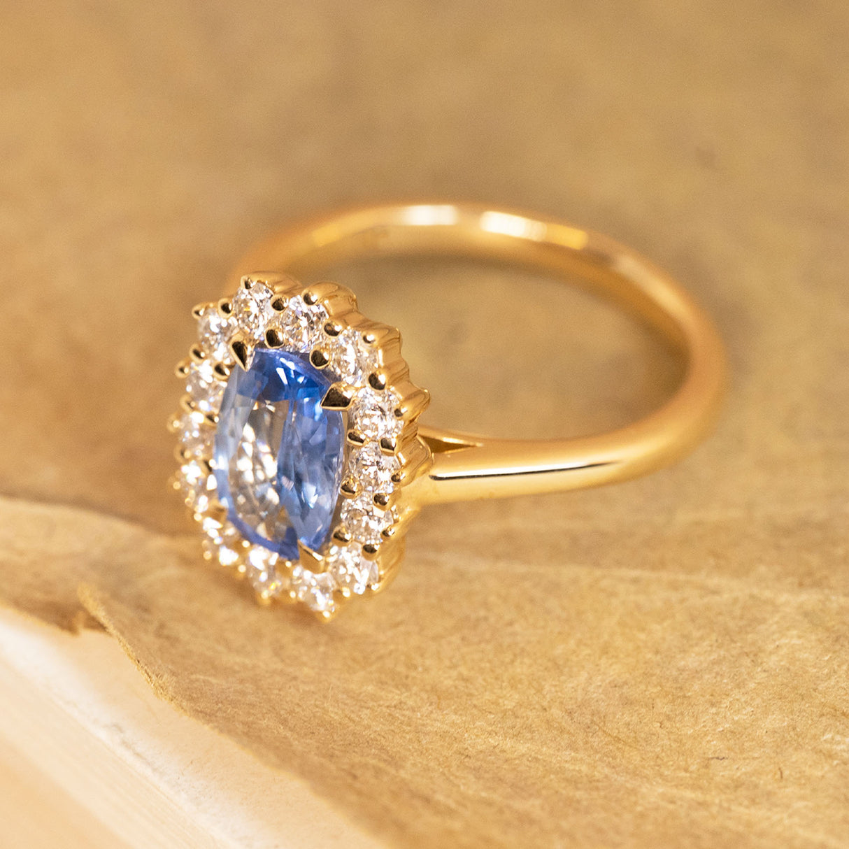 Sky blue sapphire and diamond cluster ring showcasing a luminous elongated sapphire framed by brilliant white diamonds and a refined gold band.
