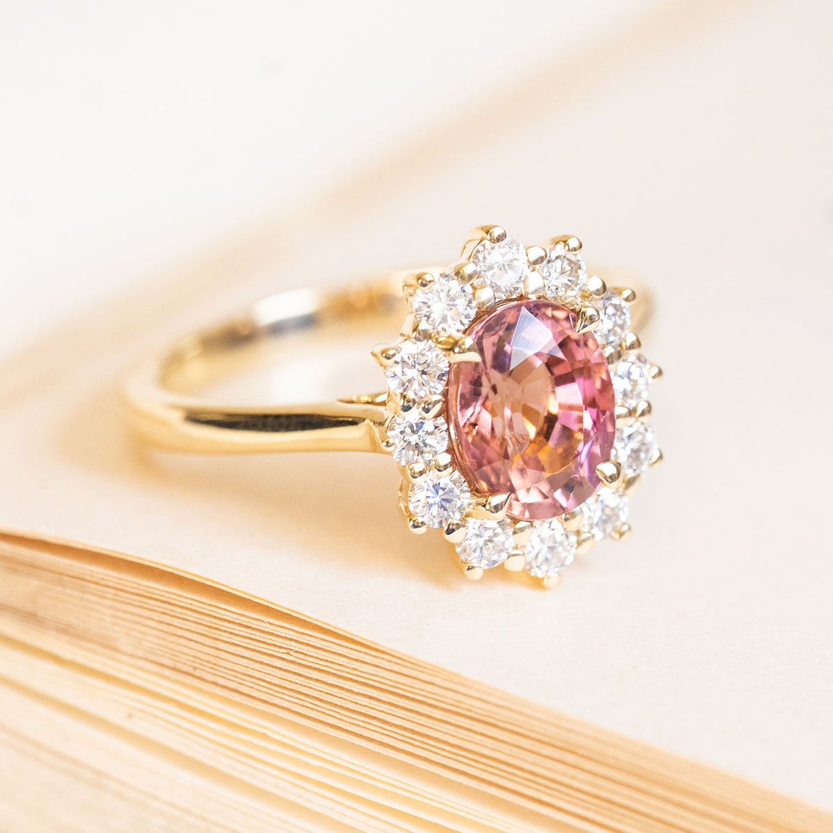 Antique-inspired rose-pink tourmaline and diamond cluster engagement ring with oval centre stone and diamond halo.