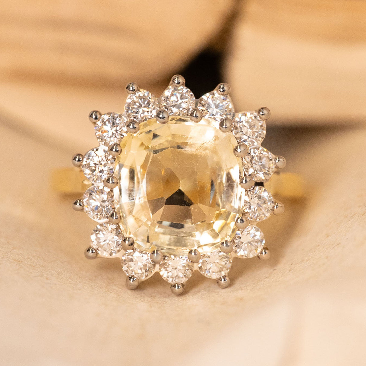 Antique inspired yellow Ceylon sapphire and diamond cluster engagement ring with an oval yellow sapphire surrounded by brilliant cut diamonds in yellow gold.