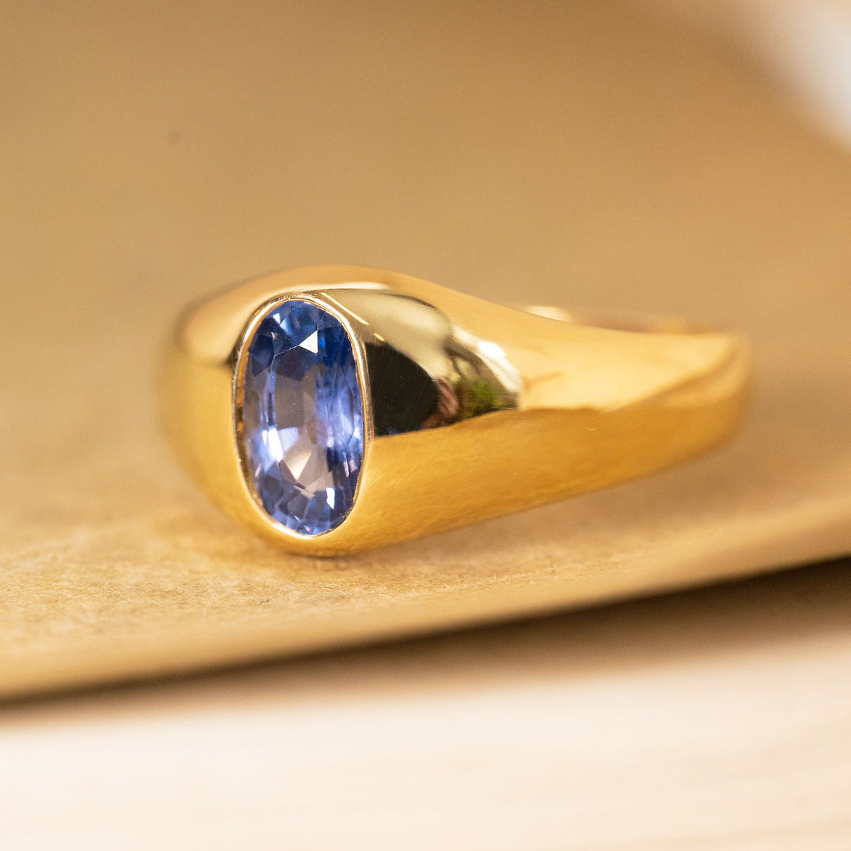 Antique iris-blue sapphire ring with a bezel-set sapphire framed by smooth flowing gold.