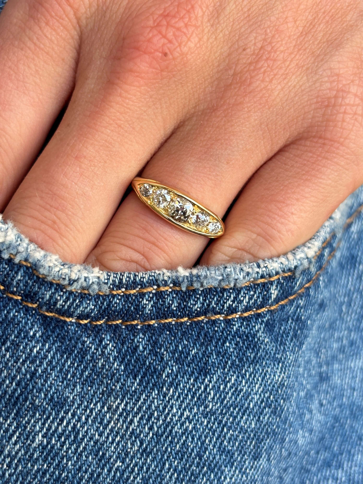 Antique Victorian old-mine cut diamond five-stone engagement ring set with five graduated old-mine cut diamonds, worn on a hand.