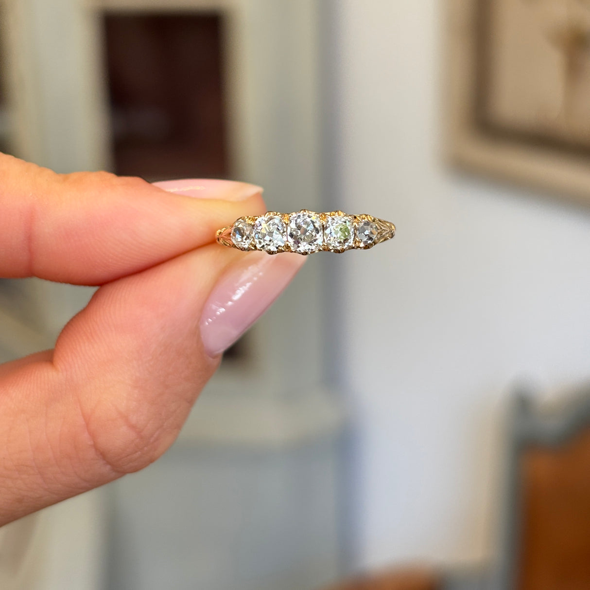 Antique Victorian old-mine diamond five-stone ring featuring five graduated old-mine cut diamonds, held by hand.