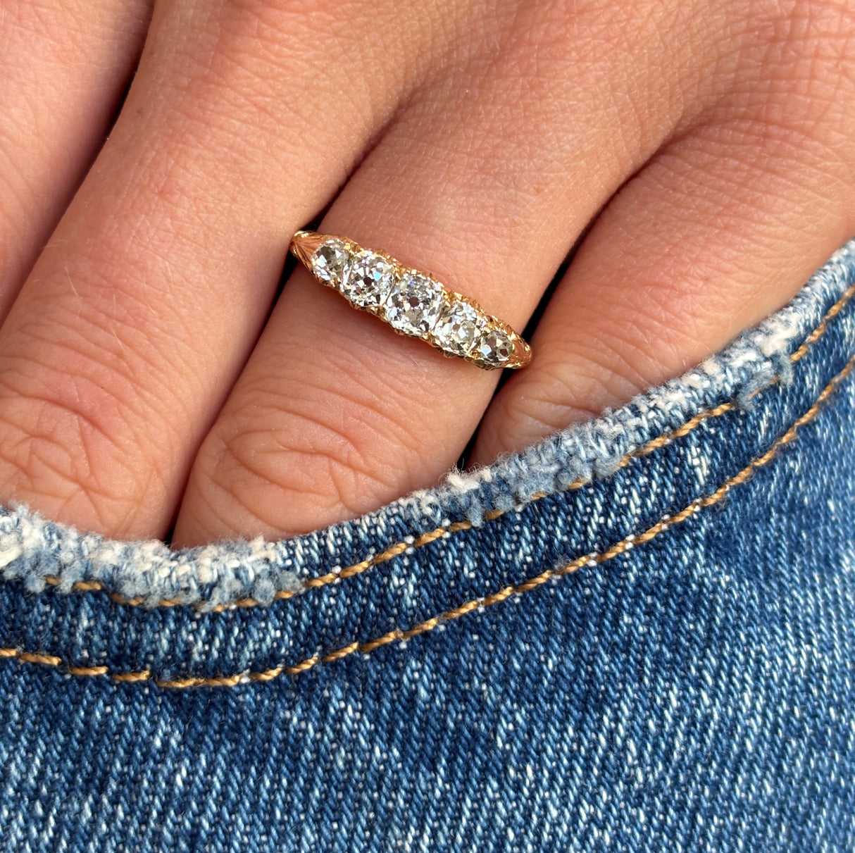 Antique Victorian old-mine diamond five-stone ring set with five graduated old-mine cut diamonds, worn on a hand.