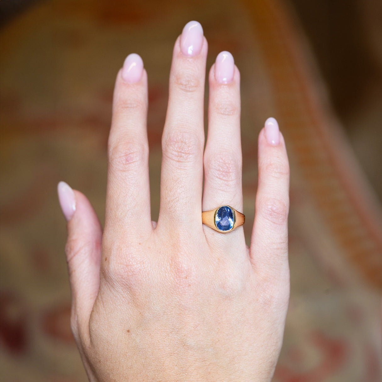 Antique Victorian sapphire single-stone ring worn on hand with oval blue sapphire and polished gold setting.