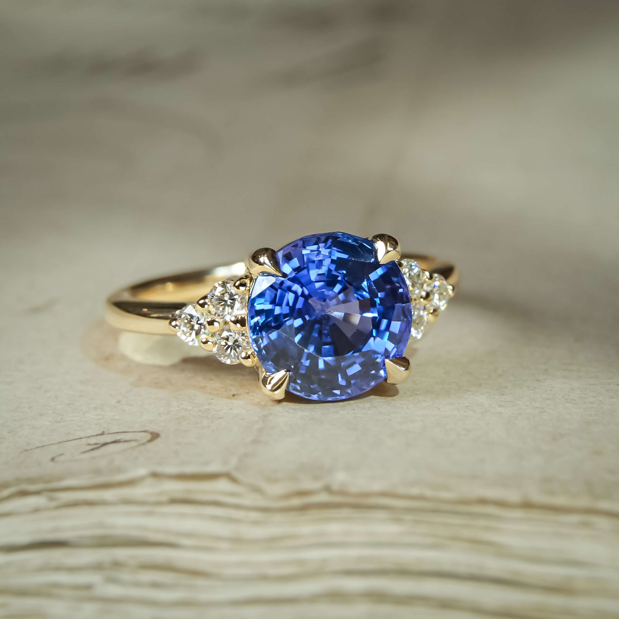 Blue sapphire three-stone ring with round centre and diamond trefoil accents