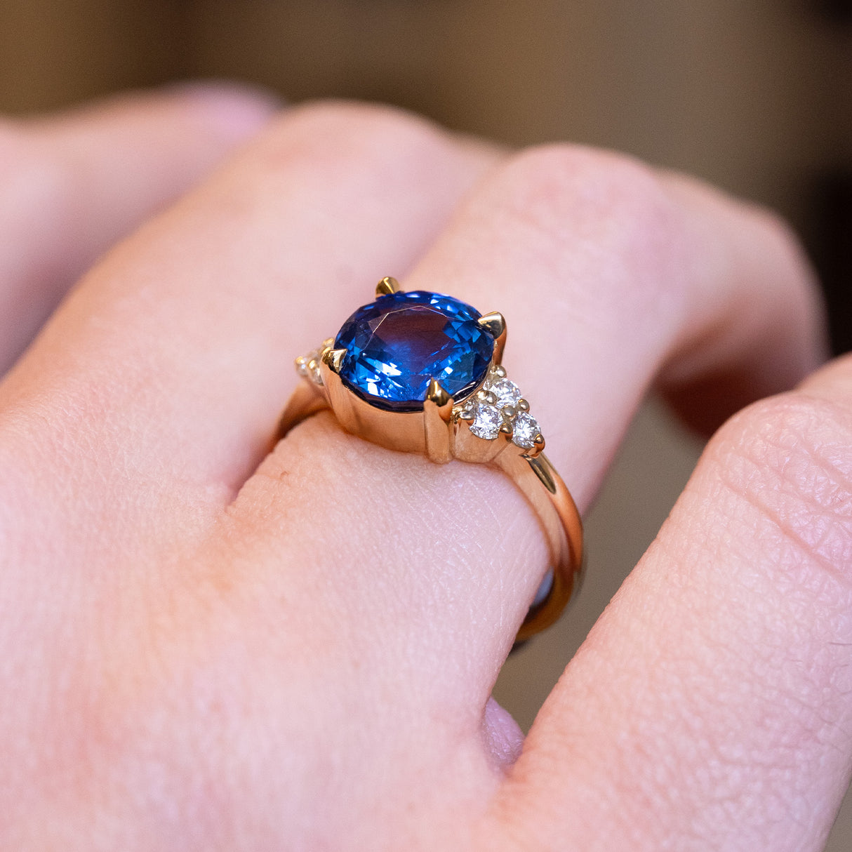 Round blue sapphire and diamond cluster tre-foil engagement ring with polished gold band and diamond accents.