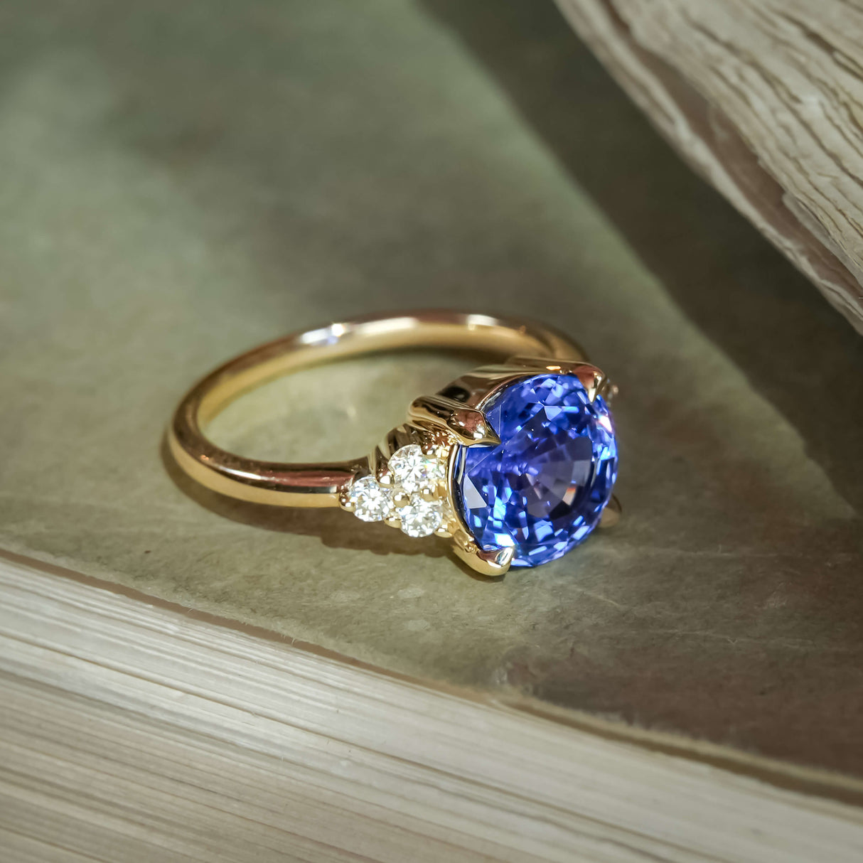 Round blue sapphire ring with diamond trefoil accents in a classic gold setting