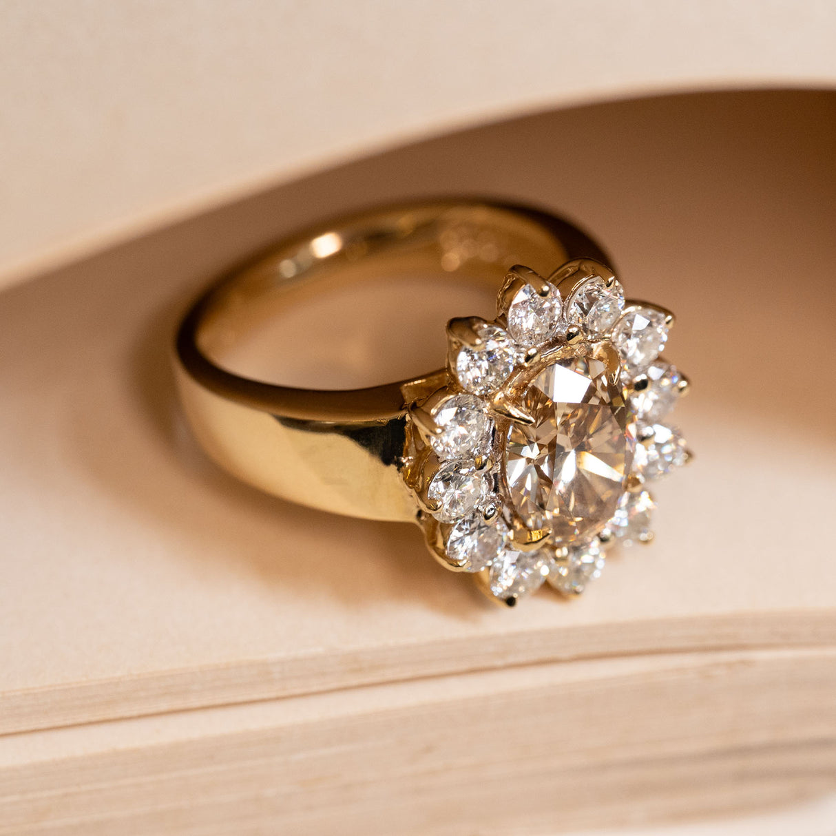 Vintage 1980s yellow gold cocktail ring showcasing an oval fancy coloured brown diamond within a brilliant-cut diamond cluster setting.