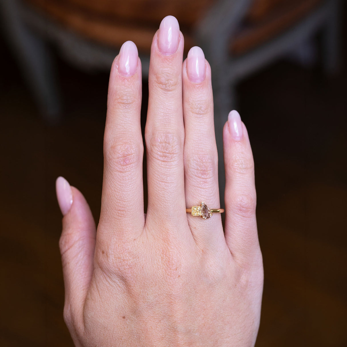 Brown and yellow diamond Toi et Moi engagement ring worn on hand with gold band.