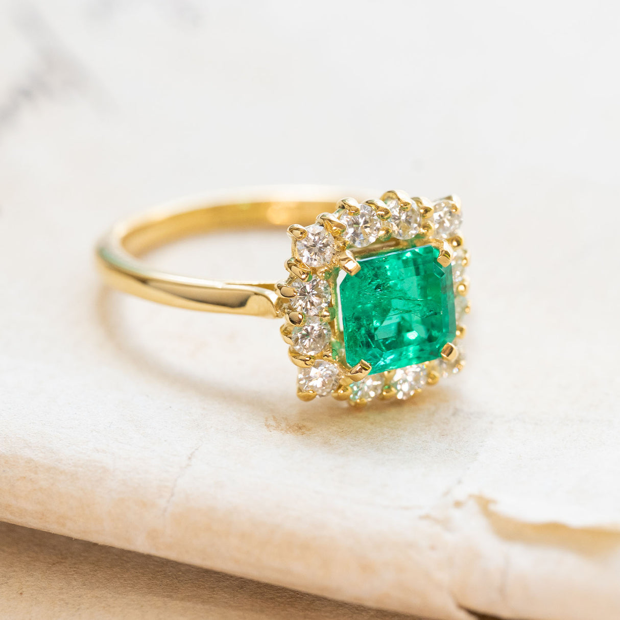 Vintage Colombian emerald and diamond cluster ring with square-cut emerald and brilliant-cut diamond halo.