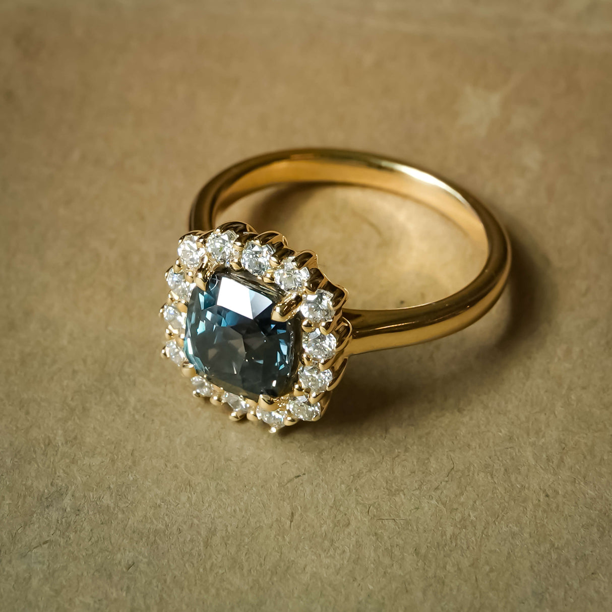 Cushion cut green sapphire and diamond cluster engagement ring in classic yellow gold setting