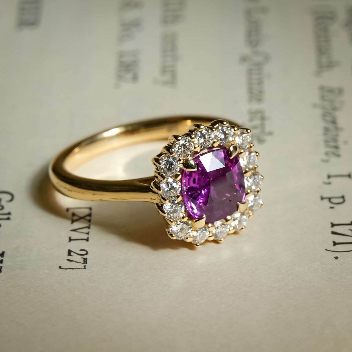 Cushion cut pink sapphire with diamond halo cluster engagement ring in yellow gold