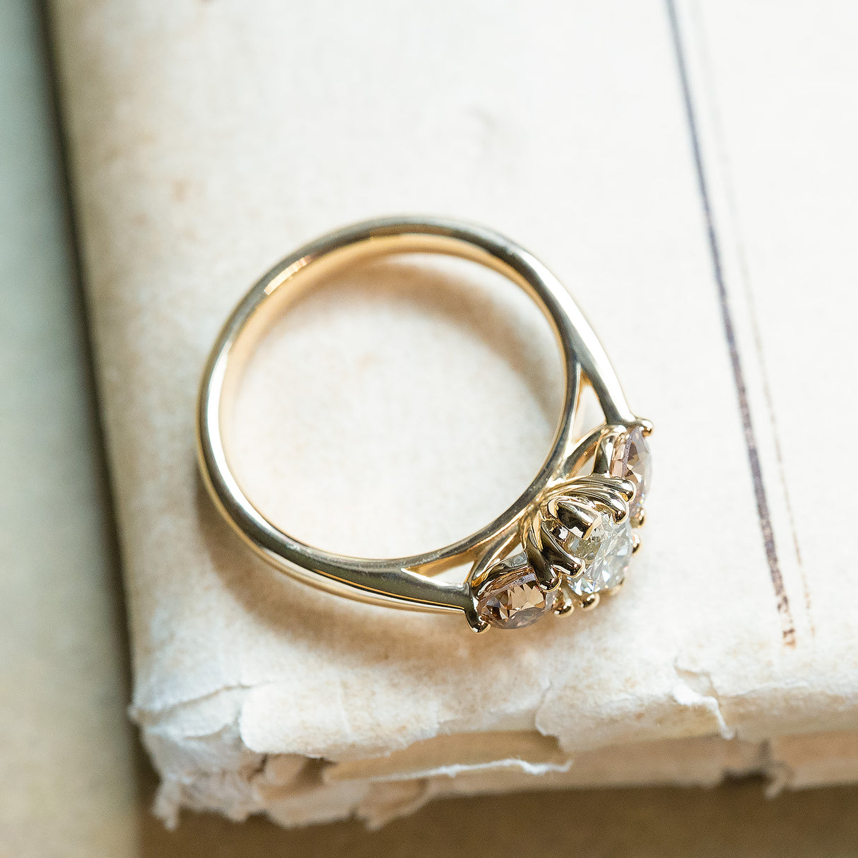 Gold diamond three-stone engagement ring showing side profile and open gallery detail.