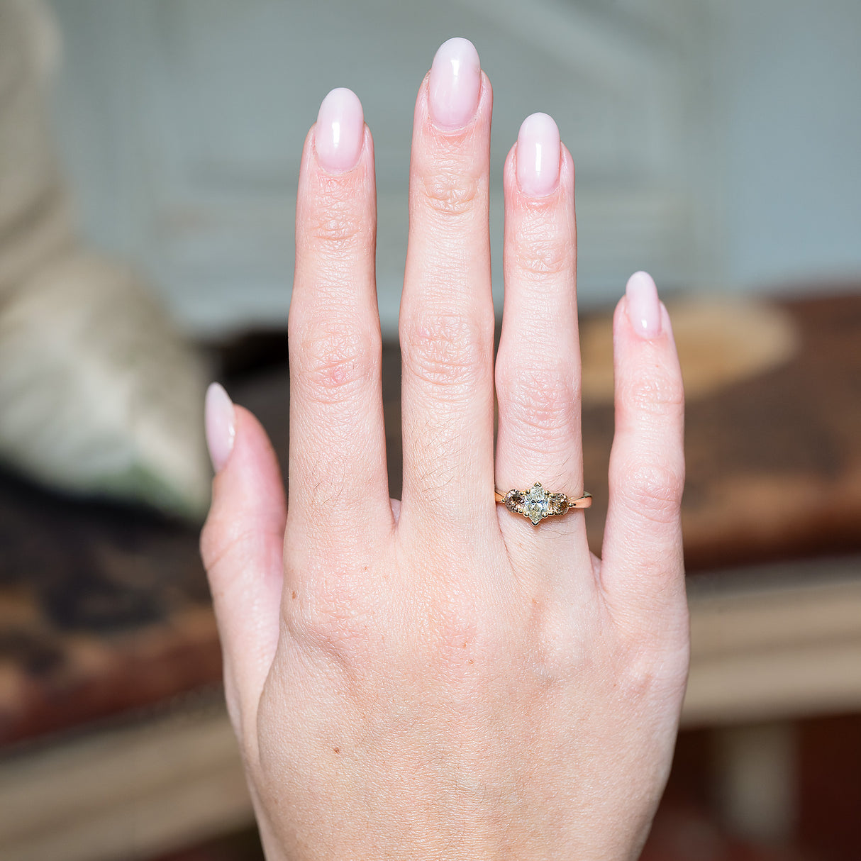 Diamond three-stone engagement ring worn on hand.
