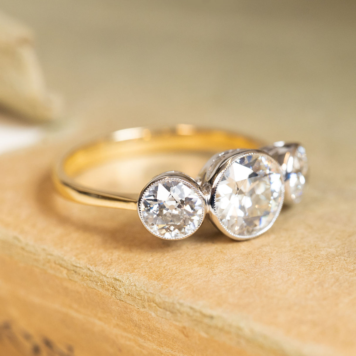 Antique Edwardian three-stone ring with old-cut diamonds and a yellow gold band.