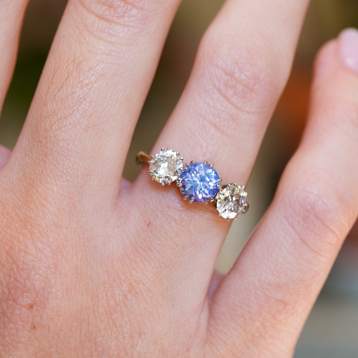 Sapphire and diamond engagement ring highlighting central purple blue stone and diamond sides.