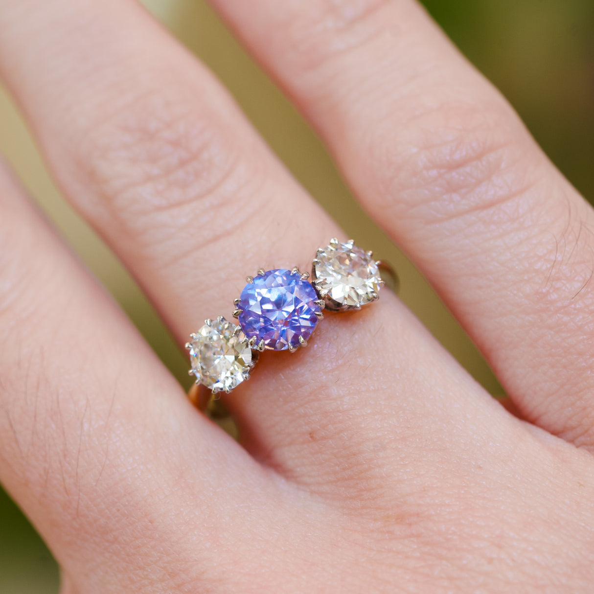 Sapphire ring with two diamonds showing delicate pastel tone and three stone design.