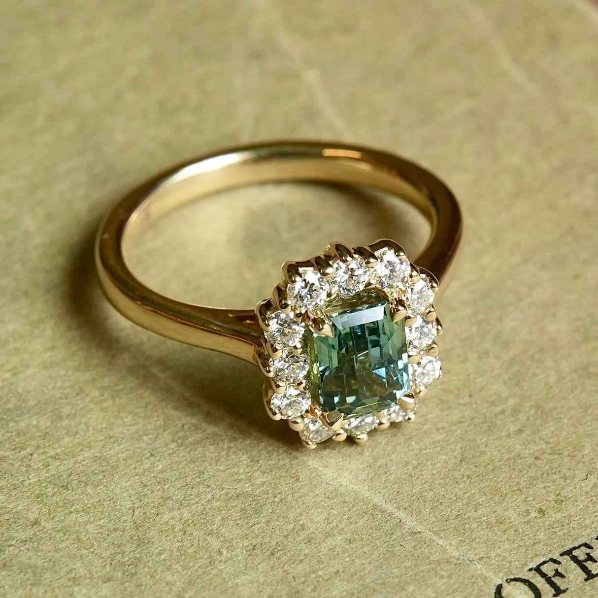 Emerald cut green sapphire centre stone engagement ring with diamond halo