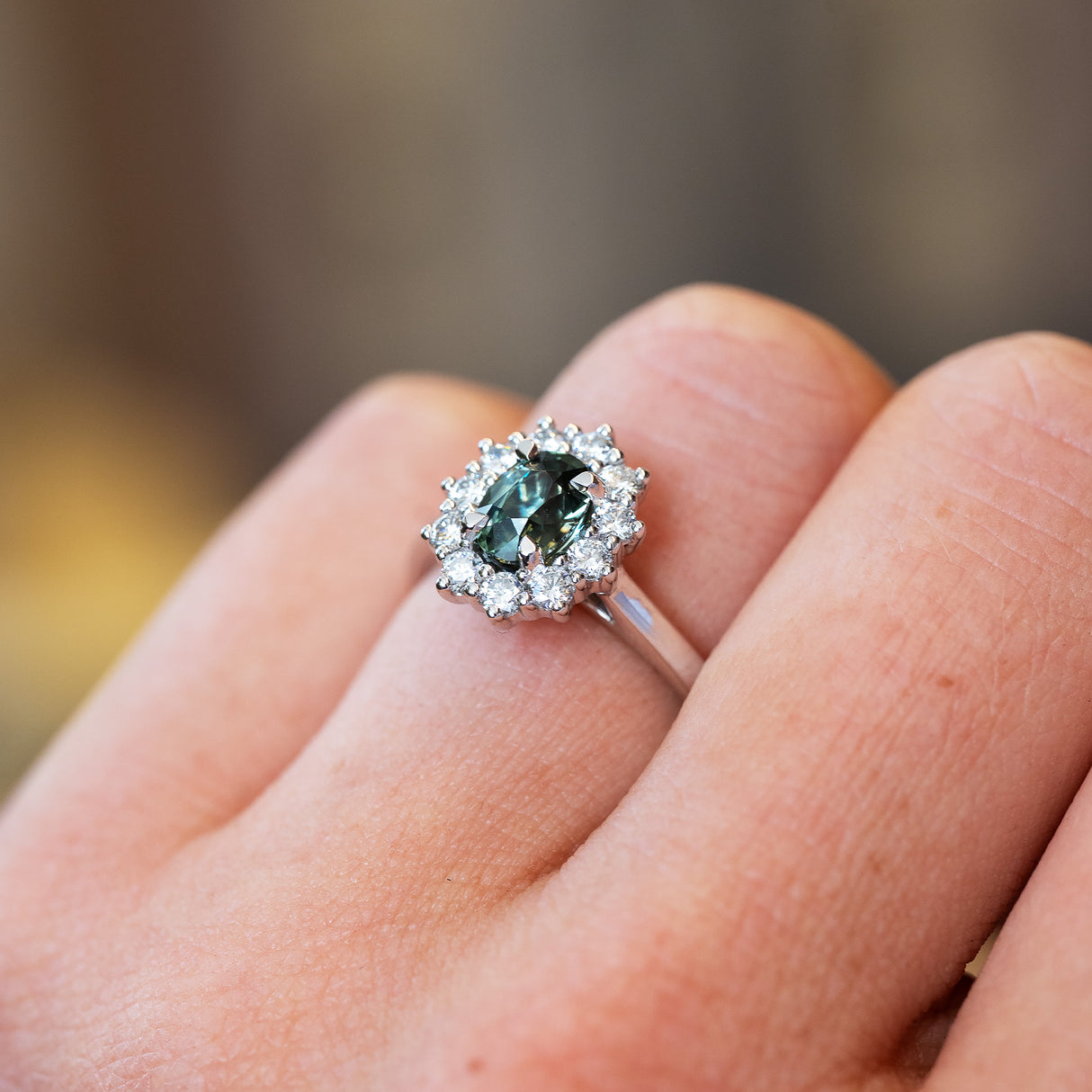 Sapphire and diamond cluster ring highlighting central green stone and surrounding diamonds.