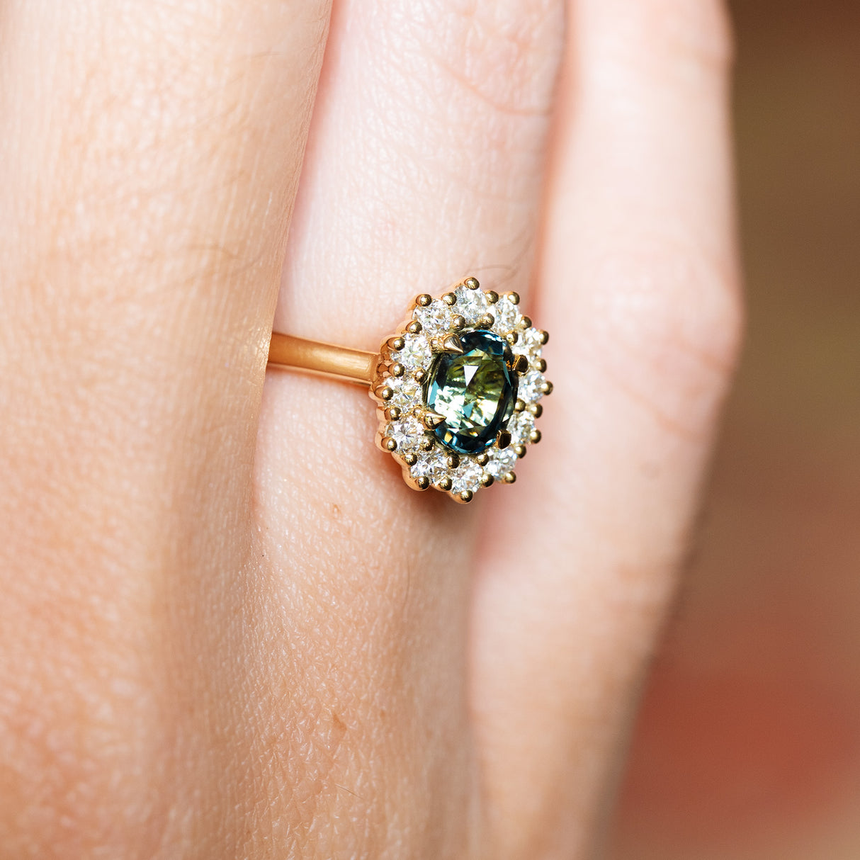 Green sapphire ring with diamond halo showing deep green tone and cluster setting.