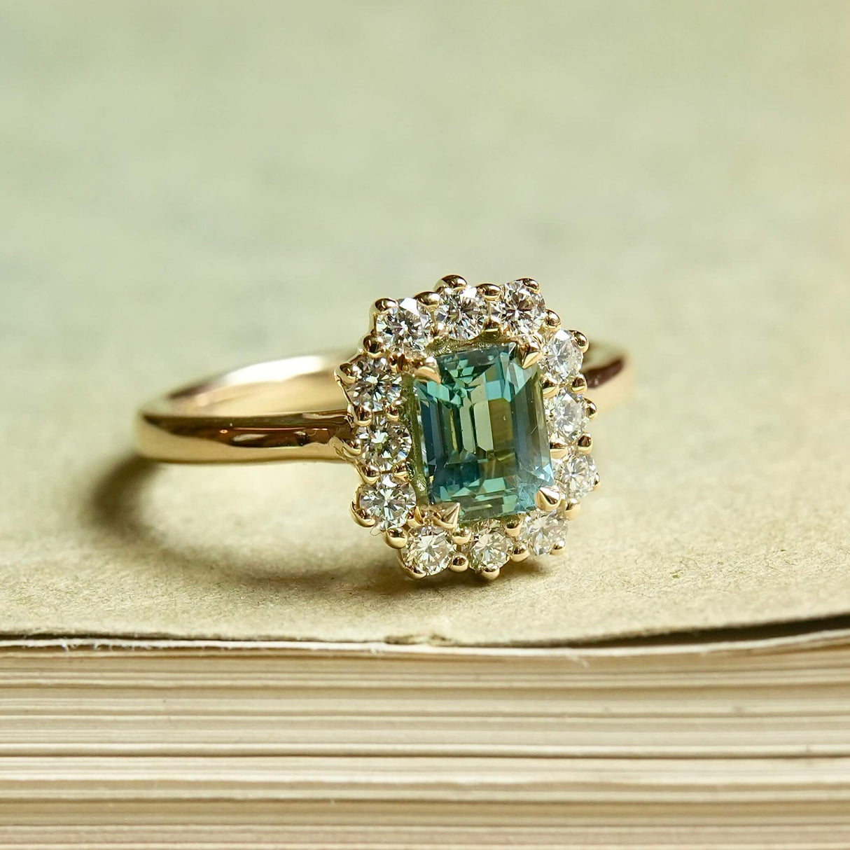 Green sapphire and diamond cluster engagement ring set in yellow gold halo design