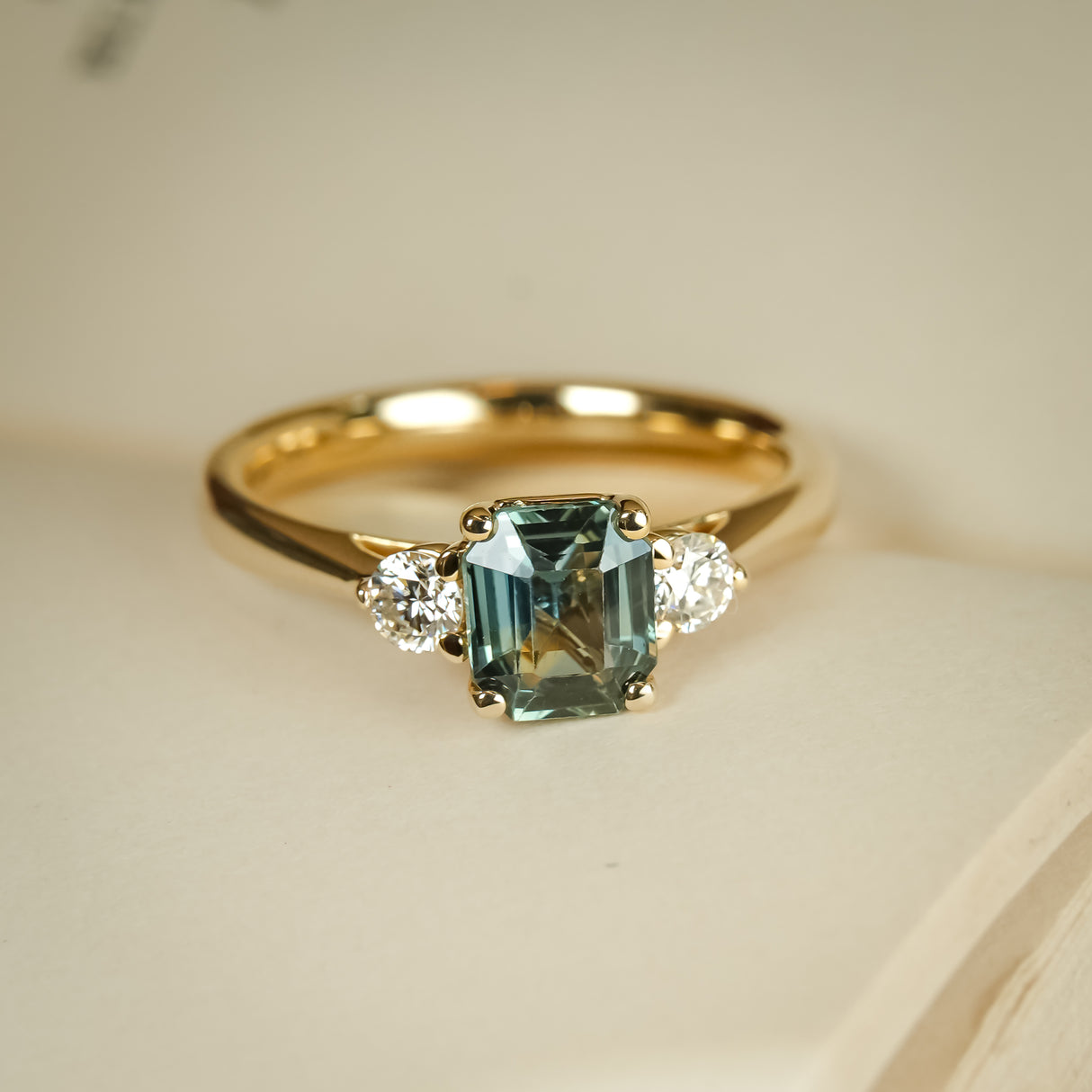 Green sapphire and diamond three stone engagement ring with yellow gold band