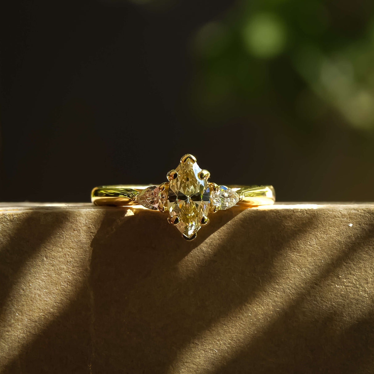 Marquise cut diamond and diamond three stone engagement ring in yellow gold setting
