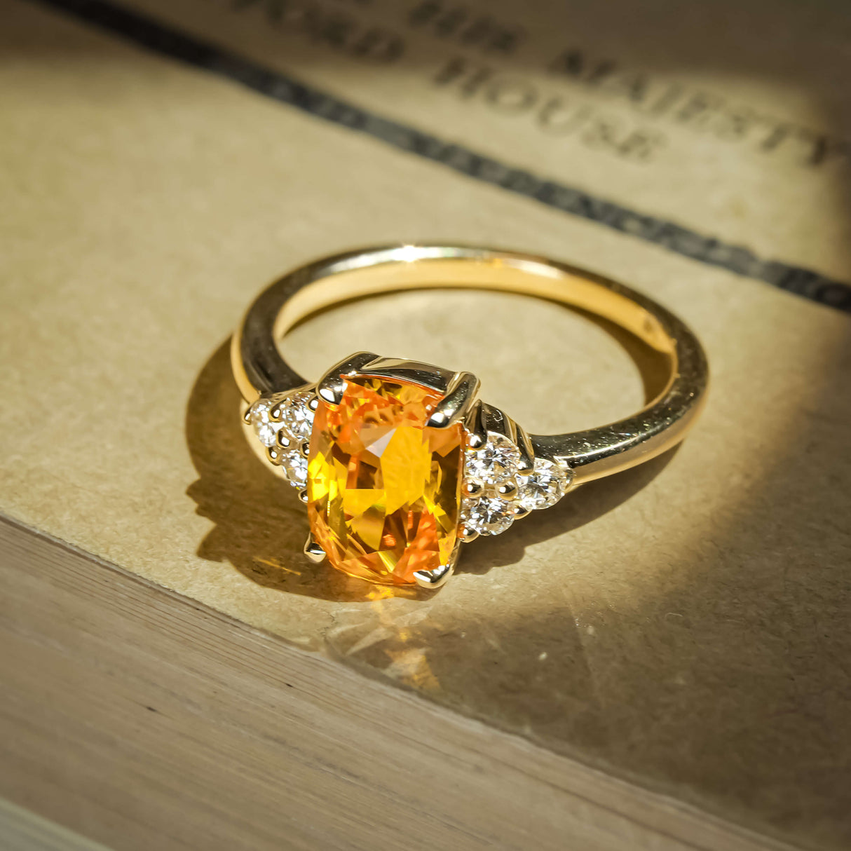 Cushion cut orange sapphire ring with diamond cluster trefoil setting