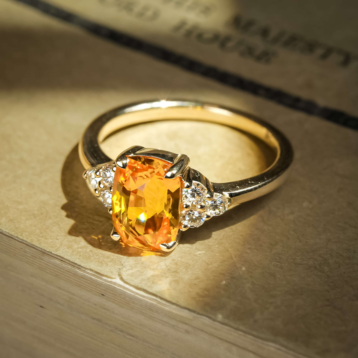 Orange sapphire ring with cushion cut gemstone and diamond trefoil cluster