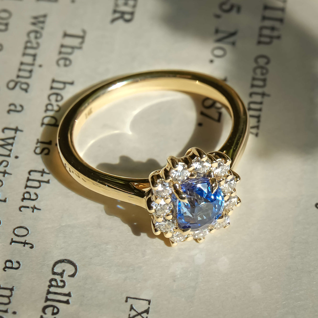 Oval royal blue sapphire with diamond cluster halo engagement ring in yellow gold