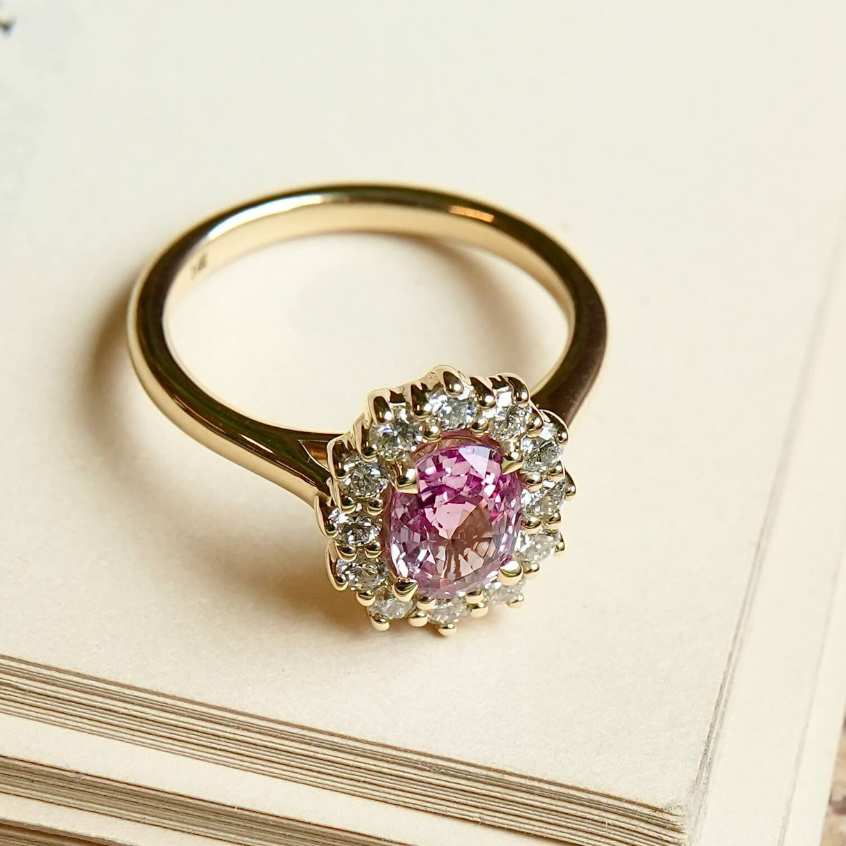 Padparadscha sapphire engagement ring surrounded by diamond cluster halo