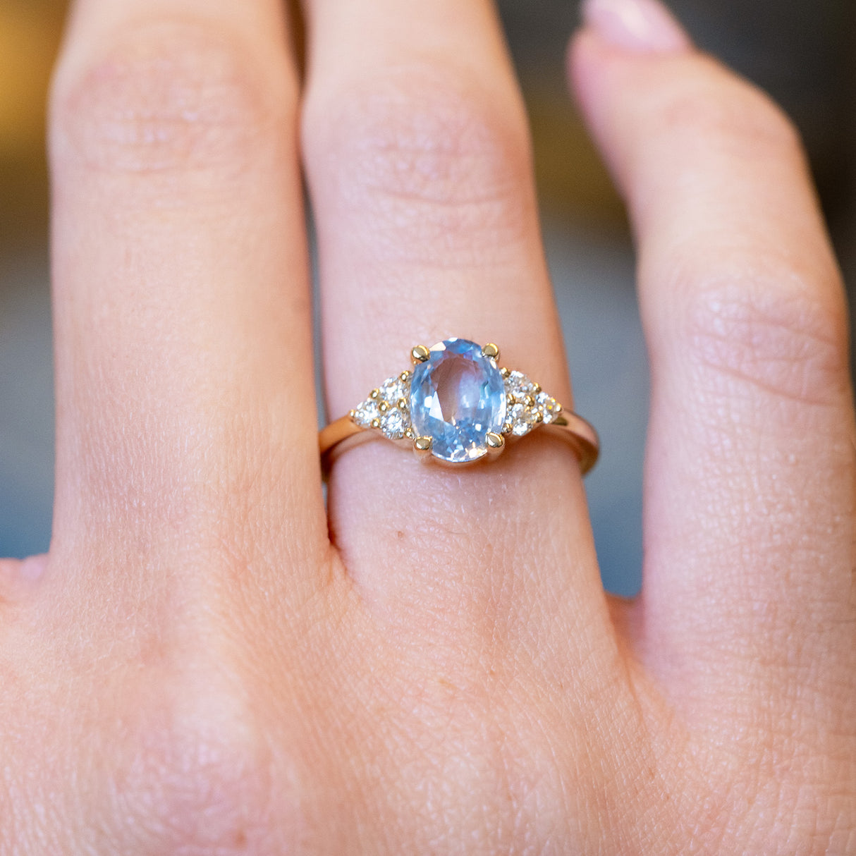 Pale blue sapphire and diamond cluster tre-foil engagement ring with oval sapphire and diamond-set shoulders.