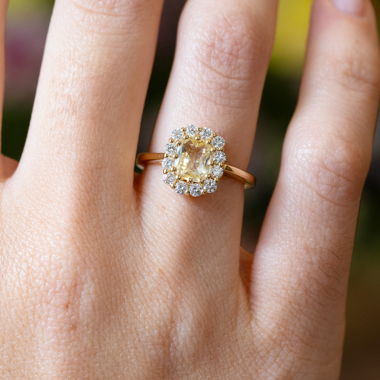 Pale yellow sapphire and diamond cluster engagement ring with diamond halo and gold band.