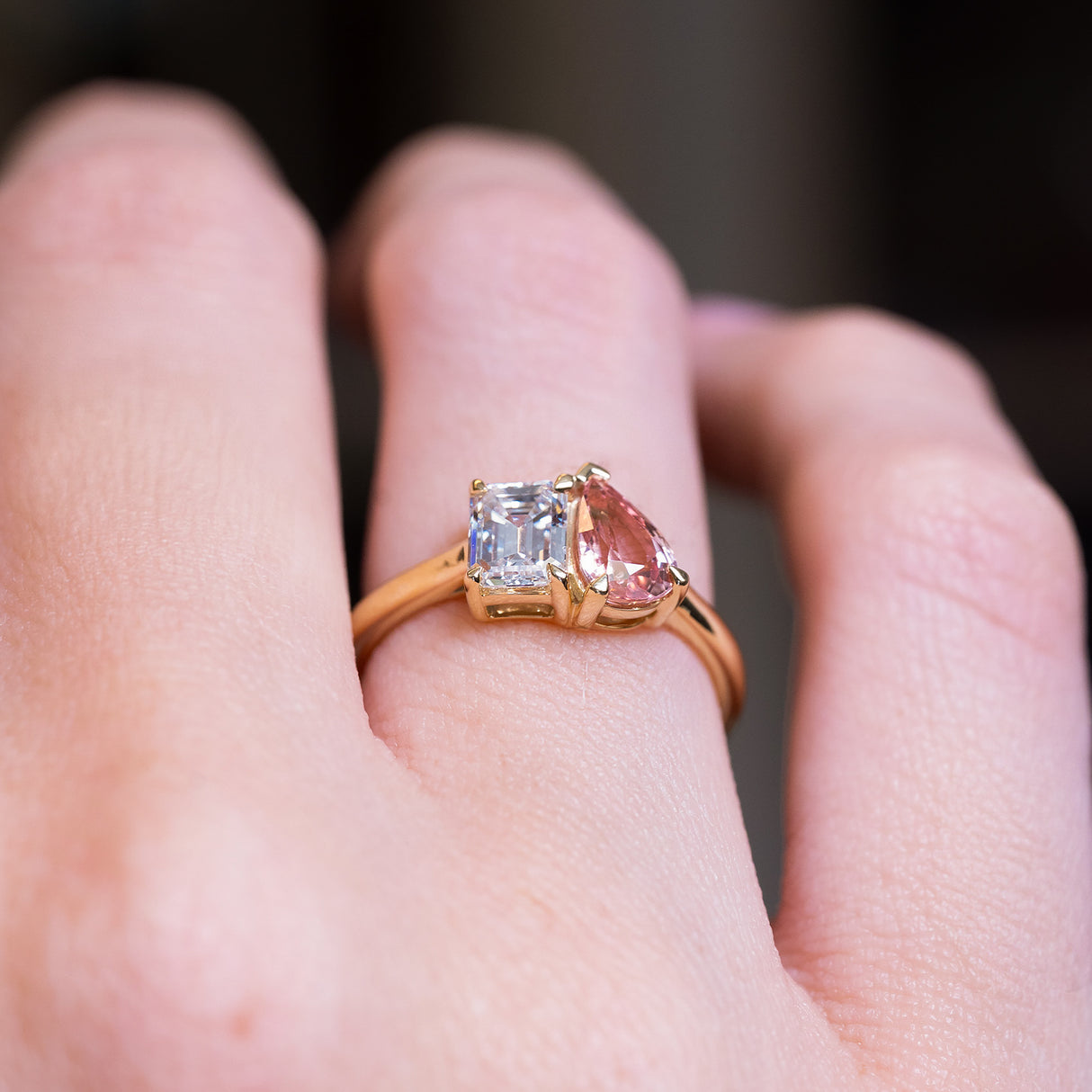 Peach coloured sapphire and diamond Toi et Moi engagement ring with asymmetrical pear sapphire and emerald cut diamond.
