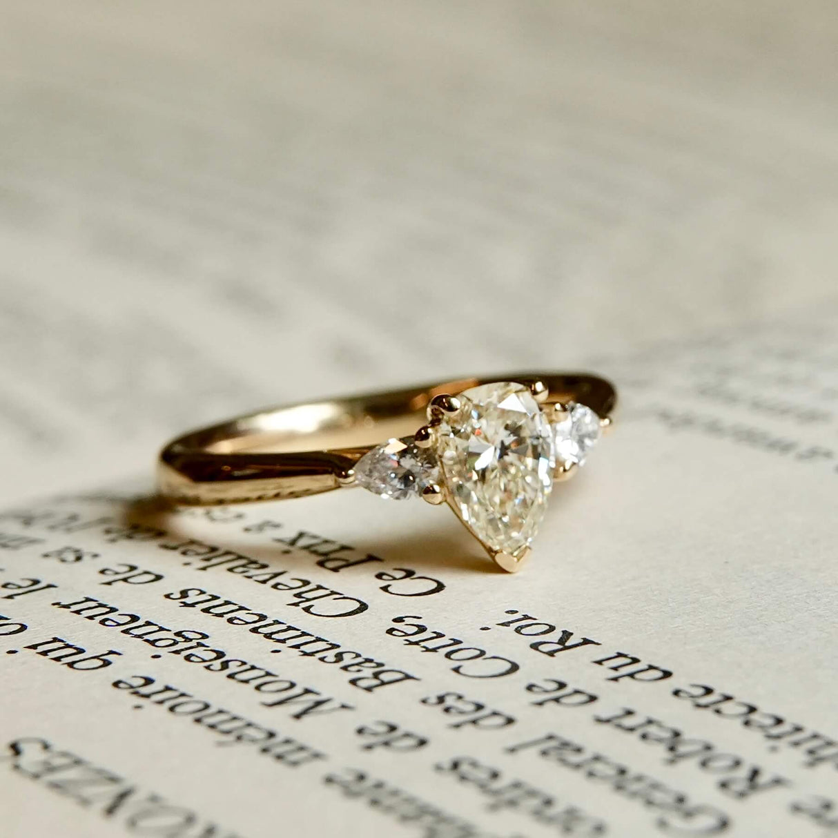 Pear cut diamond engagement ring with diamond side stones in yellow gold