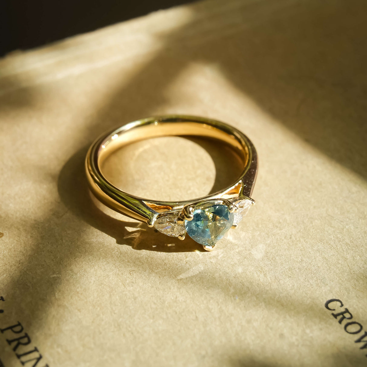 Pear cut green sapphire and diamond three stone engagement ring in yellow gold band